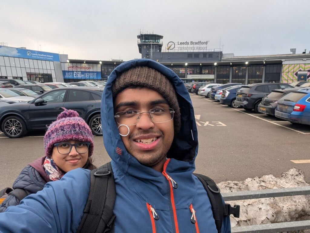 2 people standing infront of an airport